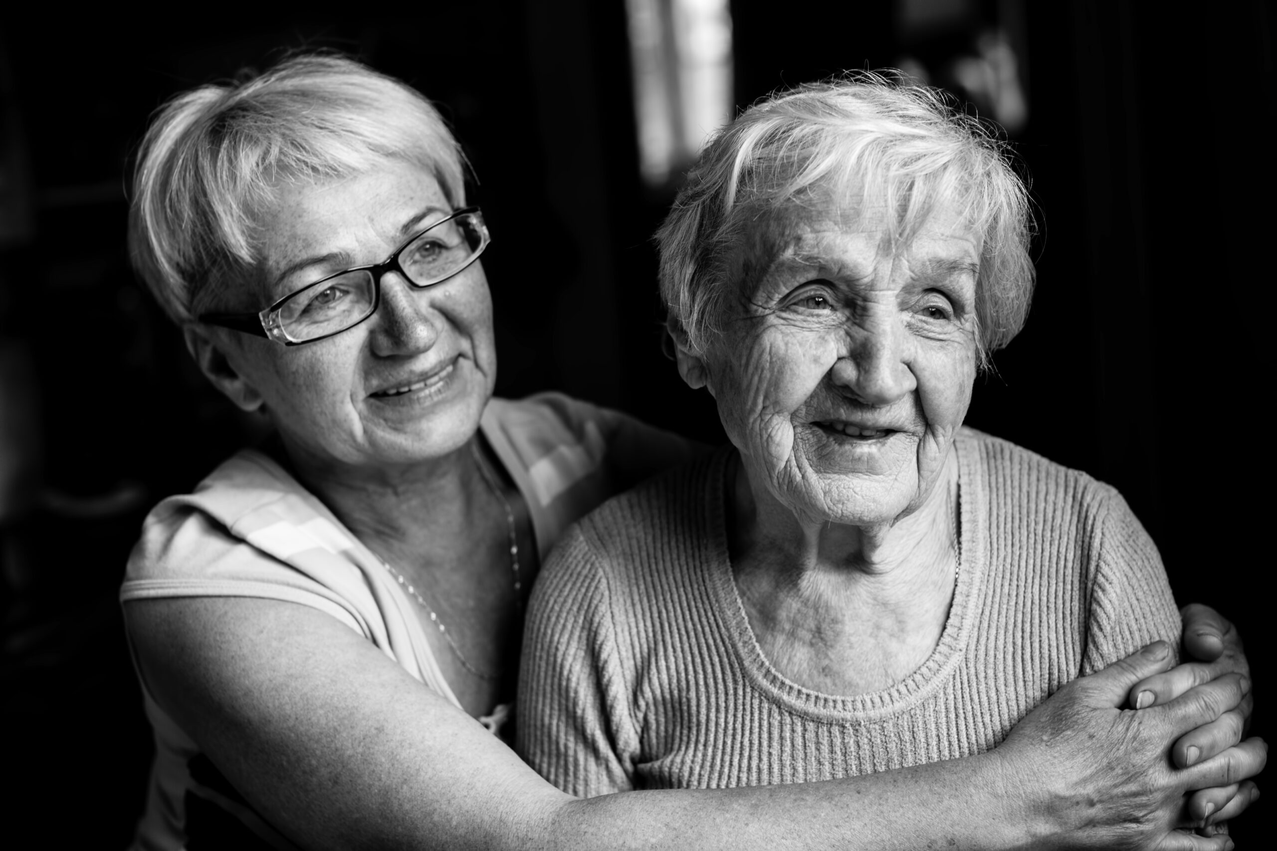 Portrait of an old woman with her adult daughter. Black and white photography.